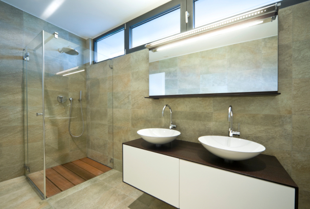 Modern bathroom with natural tile, glass shower enclosure and double sink