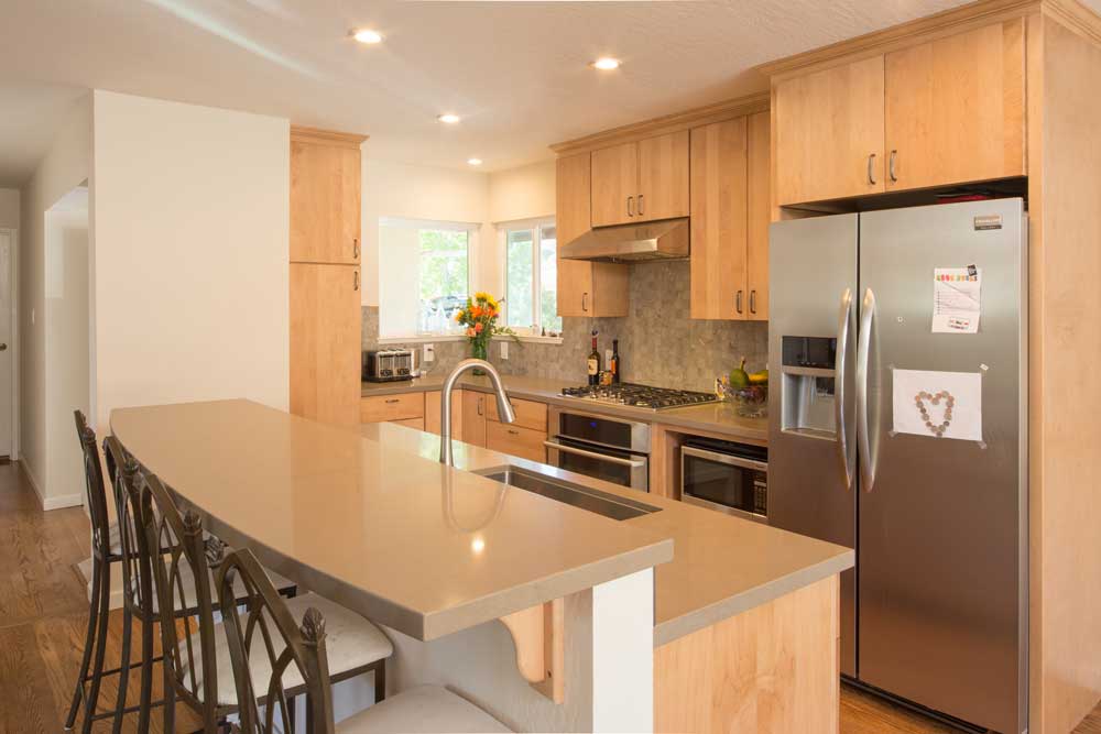 Contemporary kitchen wth warm wood cabinets, island, breakfast bar, and stainless appliances