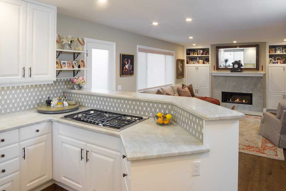 Contemporary kitchen with white cabinets and white granite countertops and contemporary great room with modern marble fireplace