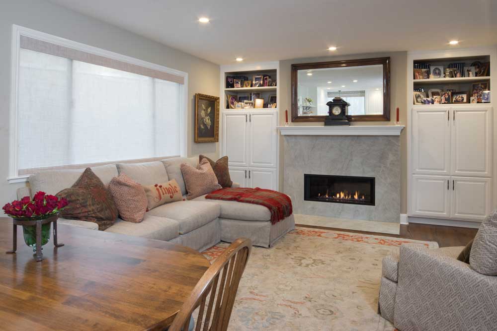 contemporary greatroom with beige couch and armchair facing modern marble fireplace with mirror above