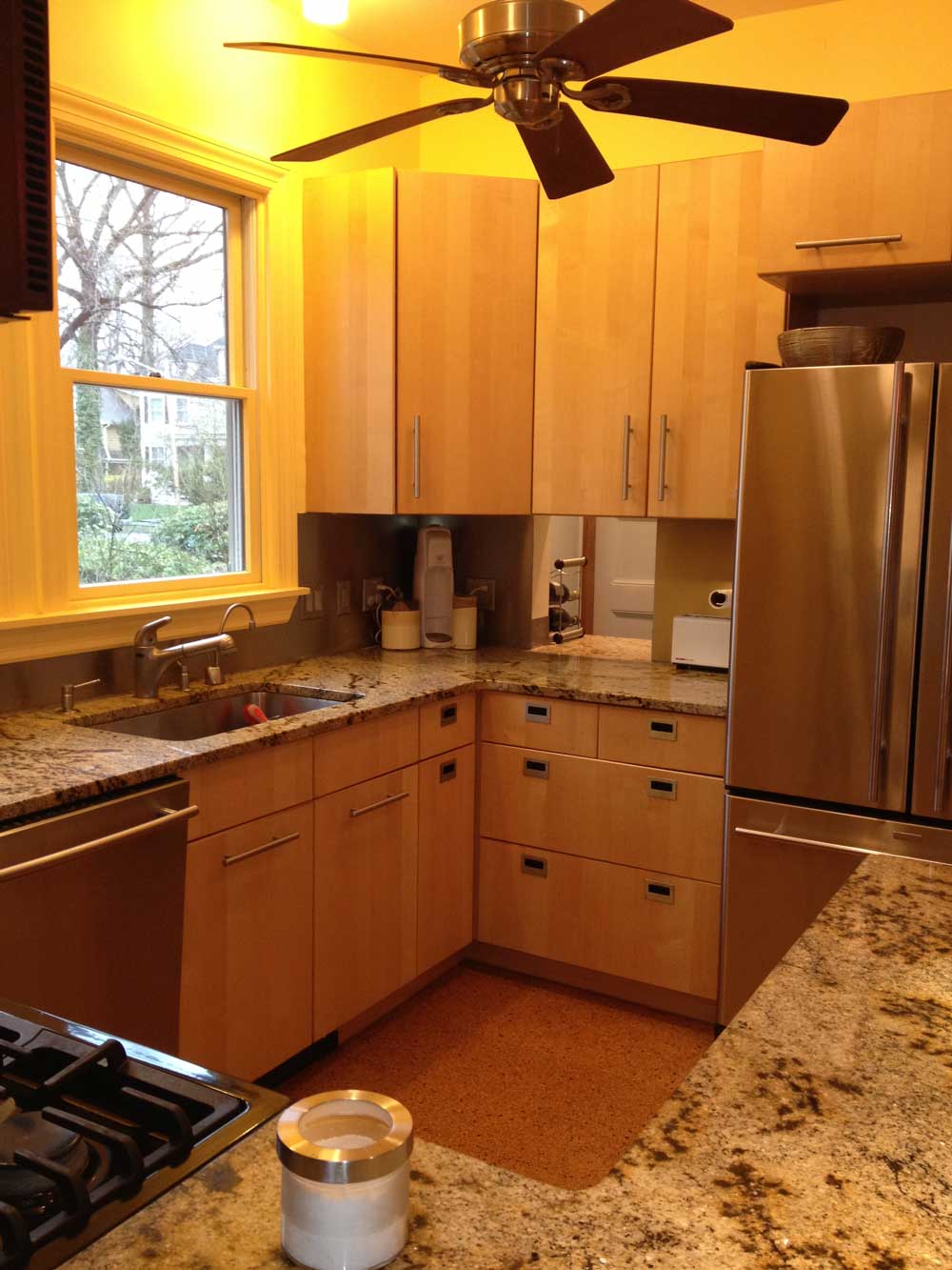 Contemporary kitchen with warm wood cabinets, granite countertops and ceiling fan