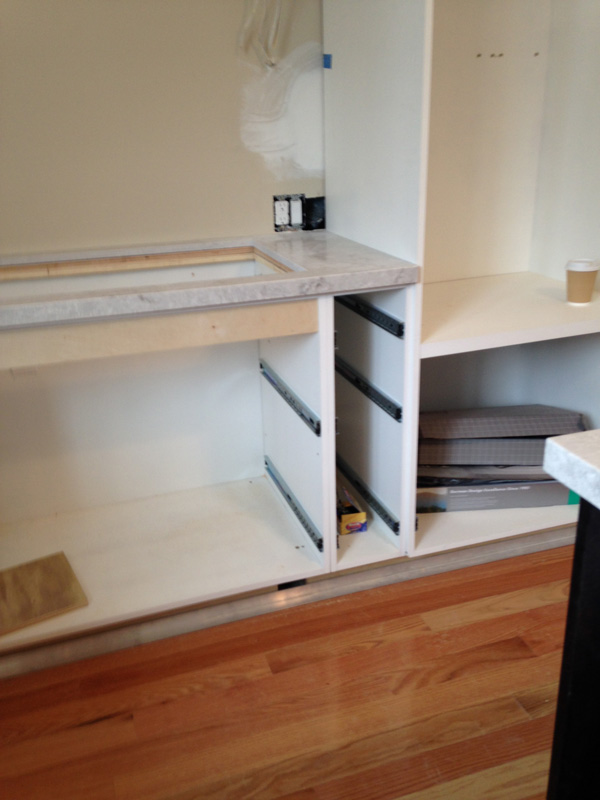 partially built kitchen cabinet with white granite countertop and hole for sink