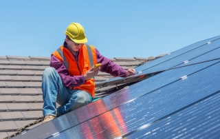 Man installing solar panels on rooftop.