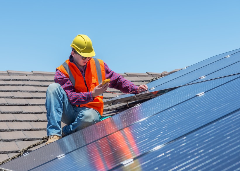 Man installing solar panels on rooftop.