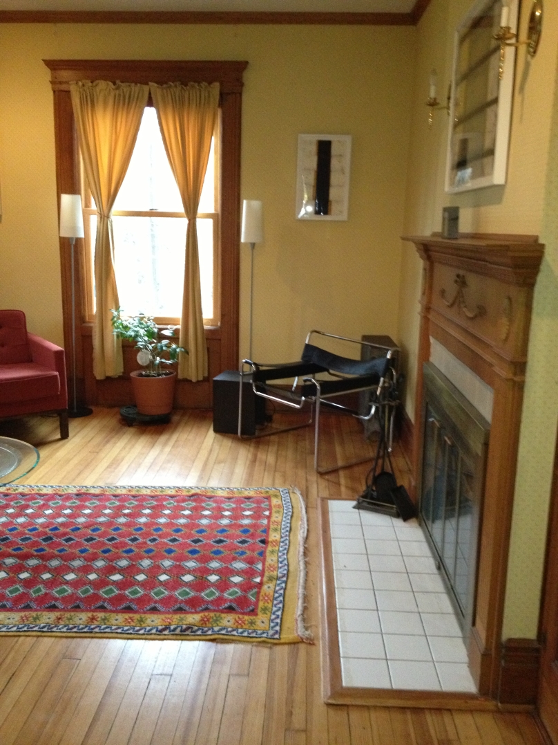 Victorian living room with decorative wood fireplace surround and wood floors