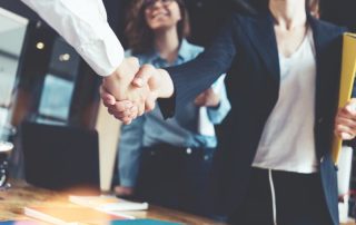 Female architect shaking hands with man, assistant in background