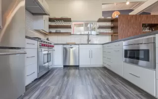 Modern kitchen with wood floors, white cabinetry and wood open shelving.