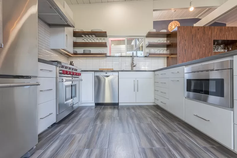 Modern kitchen with wood floors, white cabinetry and wood open shelving.