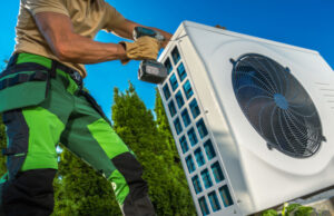 Caucasian Professional HVAC Technician Installing Large Heat Pump in a Backyard. Modern House Heating and Cooling Systems.