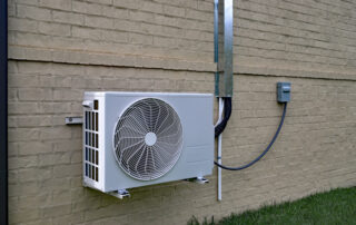 Air Conditioner mini split system next to home with painted brick wall