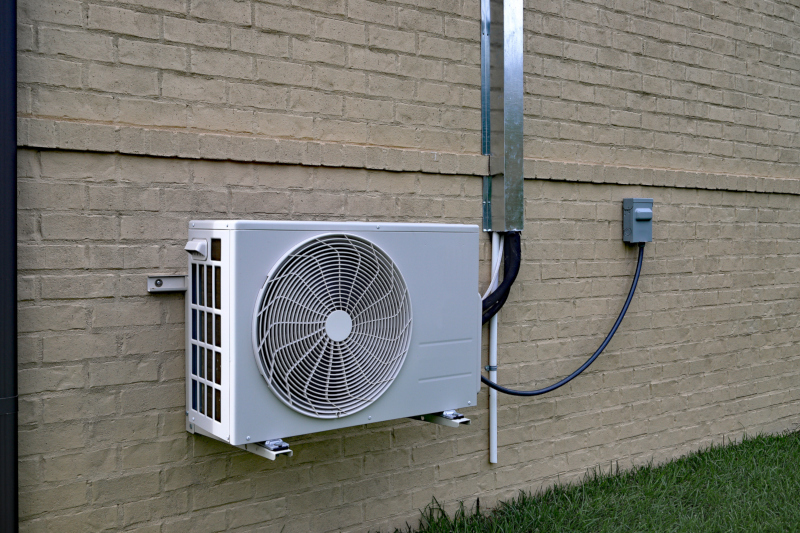 Air Conditioner mini split system next to home with painted brick wall