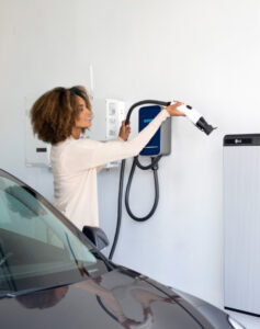 Woman plugging EV charger into wall