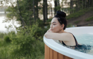 Young woman with dark hair leaning against the side of a hot tub with a relaxed expression