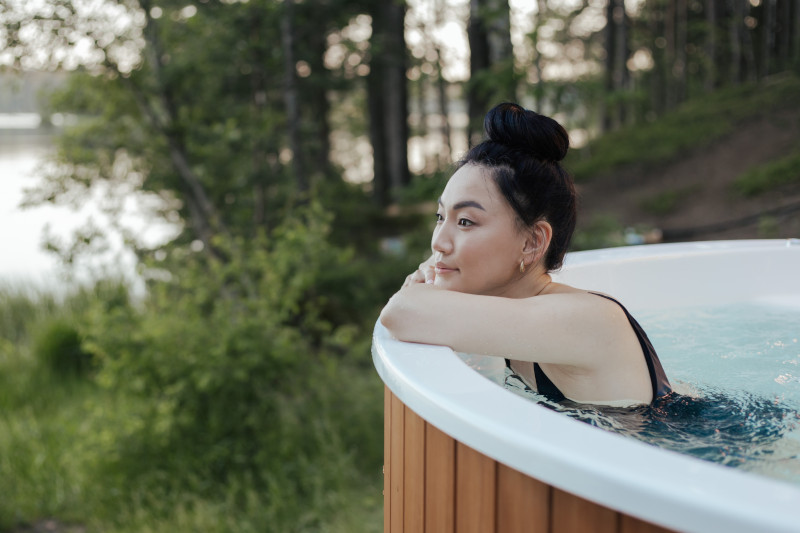 Young woman with dark hair leaning against the side of a hot tub with a relaxed expression