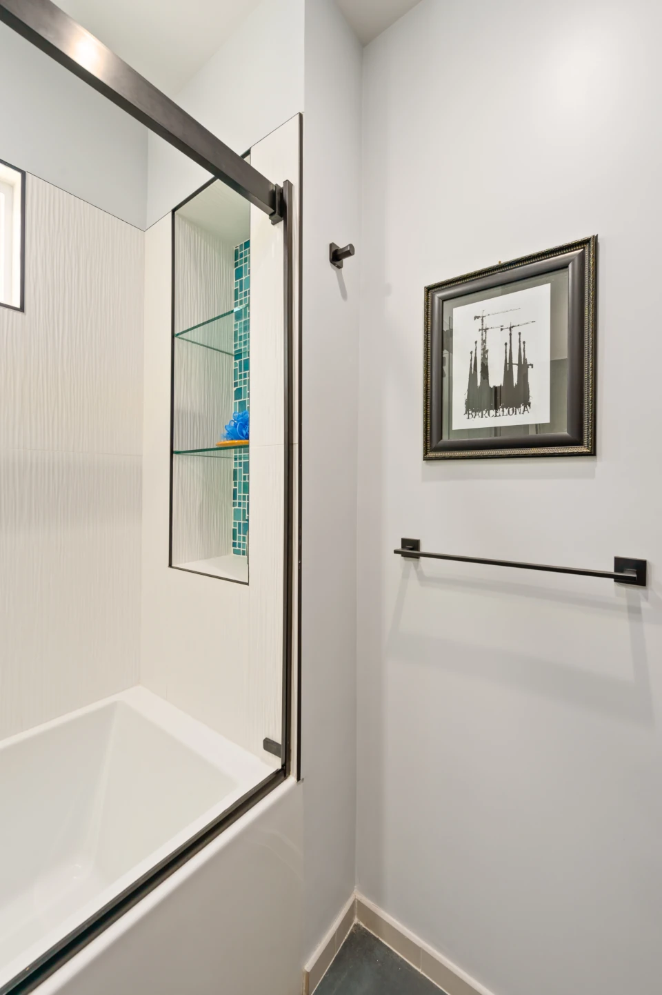 Modern bath with white soaking tub and shower enclosure and niche tiled in blue-green ceramic tile.