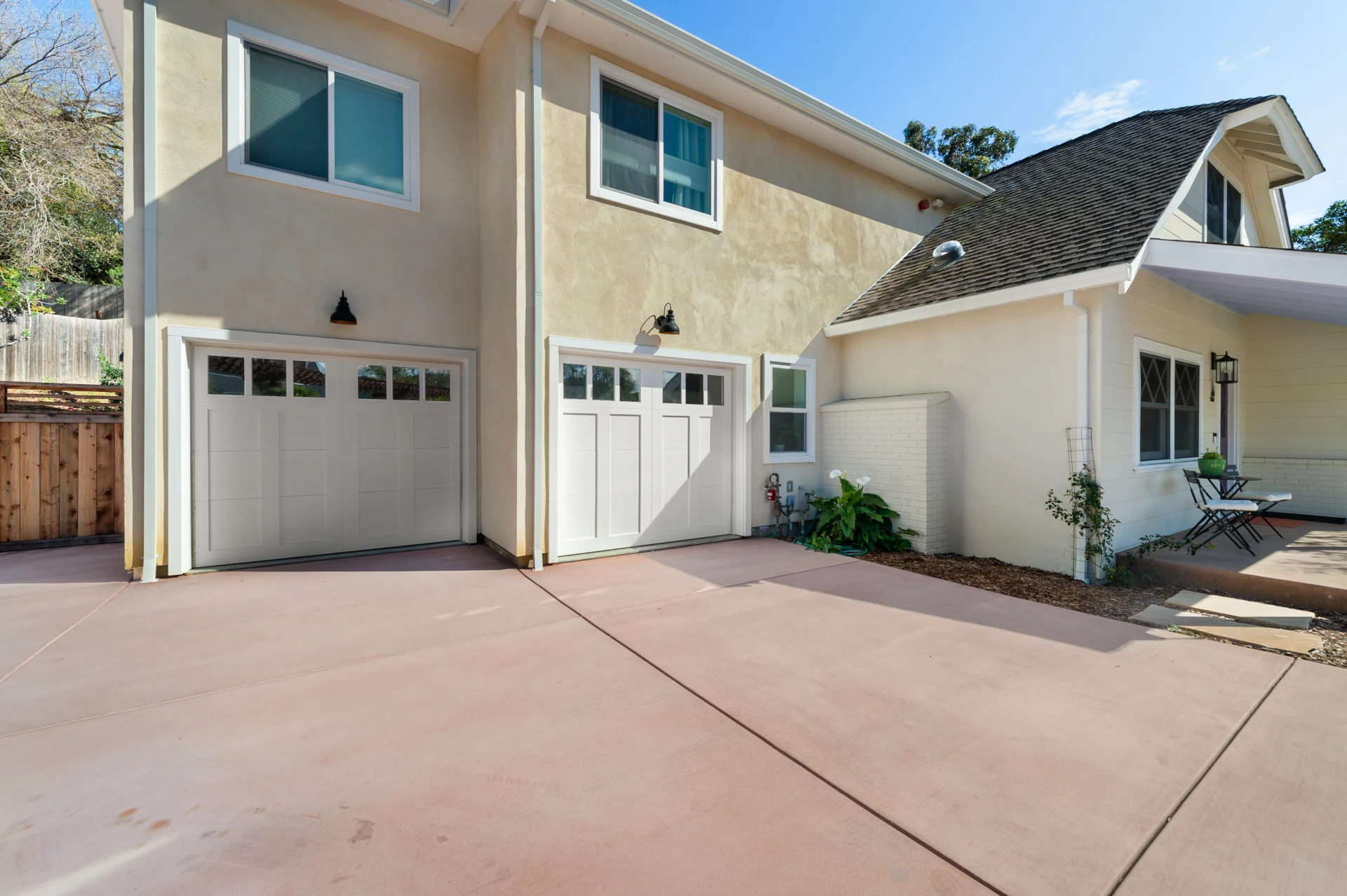 Exterior of home with two garage doors and windows above attached to a beige home with a sloped roof.