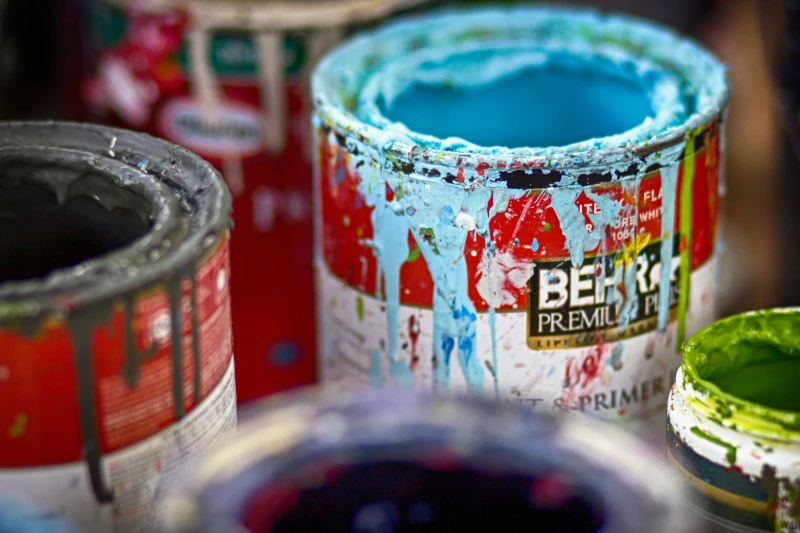 Group of open paint cans with paint dripping down sides.