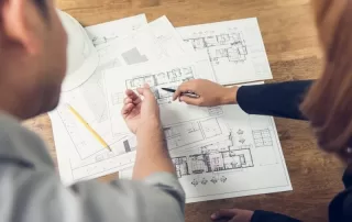 Arms of two people reviewing architectural construction documents